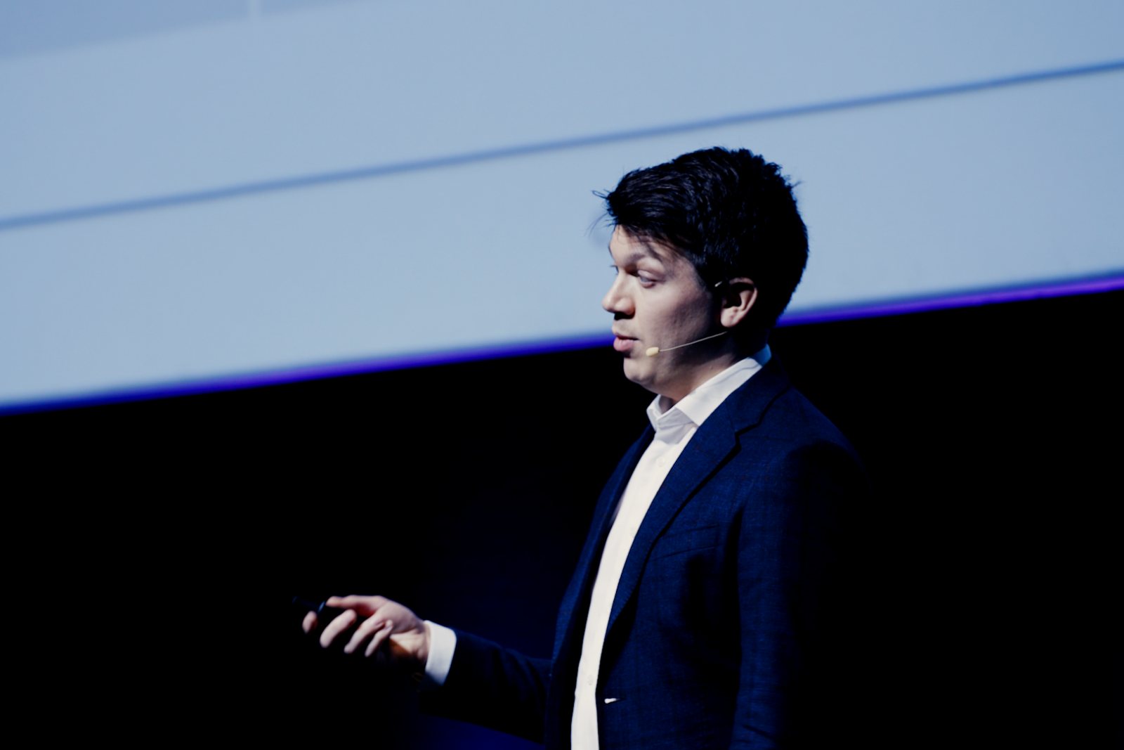 Andreas Bang Leed speaking on stage with a headset microphone